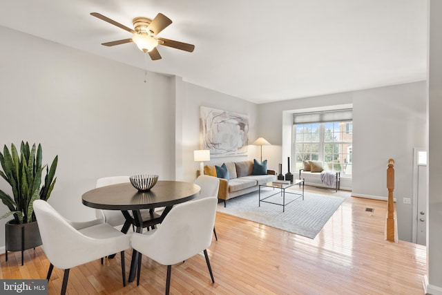 dining room with light wood-type flooring, a ceiling fan, and baseboards