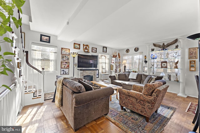 living room featuring stairs, a fireplace, and decorative columns