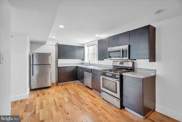 kitchen with stainless steel appliances, light countertops, light wood-style flooring, and baseboards