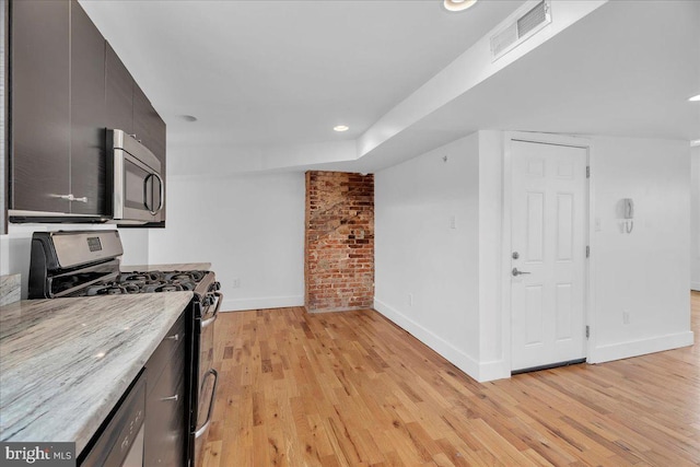 kitchen with light wood finished floors, stainless steel appliances, visible vents, modern cabinets, and baseboards