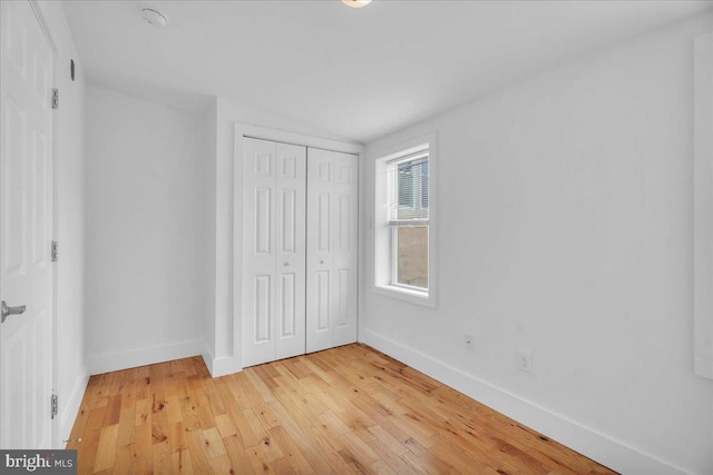 unfurnished bedroom with a closet, light wood-style flooring, and baseboards