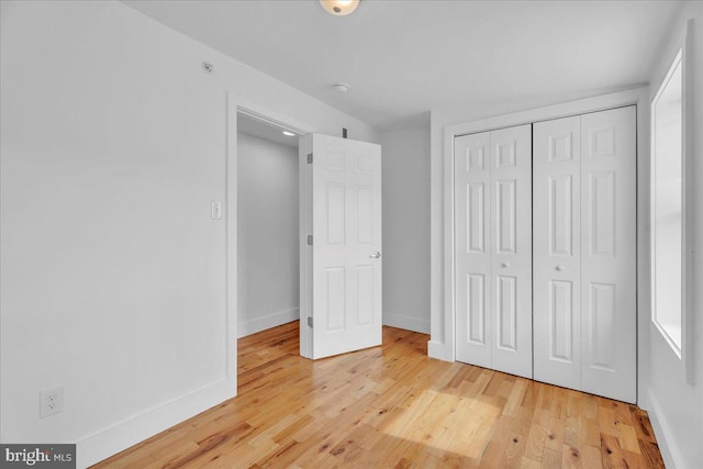 unfurnished bedroom with a closet, baseboards, and light wood finished floors