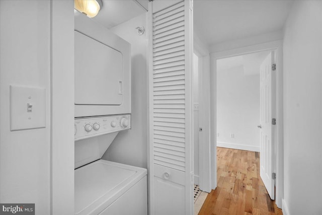 laundry room with stacked washer and dryer, light wood-style flooring, and laundry area