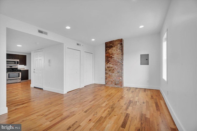 spare room featuring electric panel, visible vents, light wood-style flooring, and baseboards