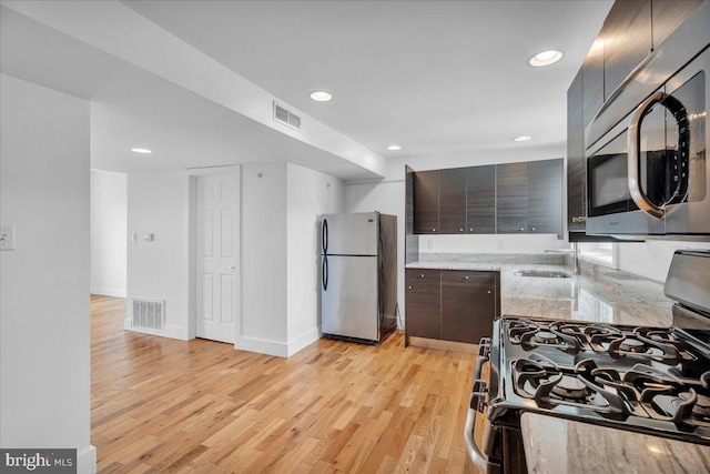 kitchen with stainless steel appliances, light wood-style flooring, modern cabinets, and visible vents