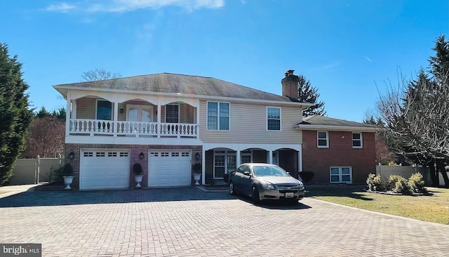 view of front of house featuring an attached garage, fence, decorative driveway, a front lawn, and a chimney