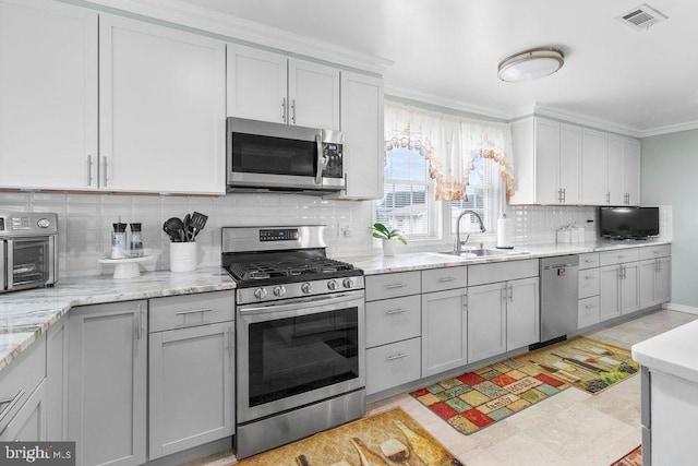 kitchen with tasteful backsplash, visible vents, appliances with stainless steel finishes, ornamental molding, and a sink