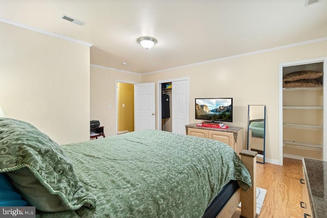 bedroom with light wood-style floors, visible vents, ornamental molding, and baseboards