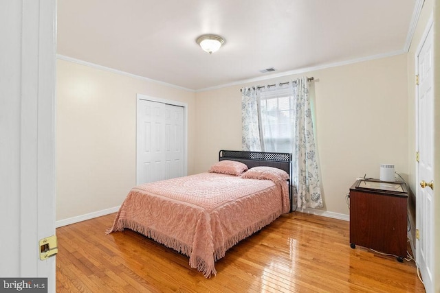 bedroom with light wood finished floors, baseboards, ornamental molding, and a closet