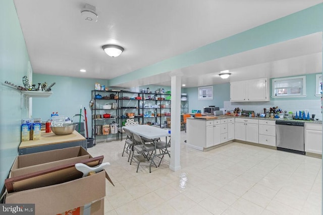 kitchen featuring white cabinetry, backsplash, stainless steel dishwasher, and light countertops