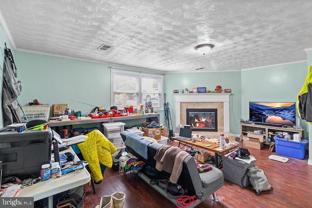 living room with a glass covered fireplace, wood finished floors, visible vents, and crown molding