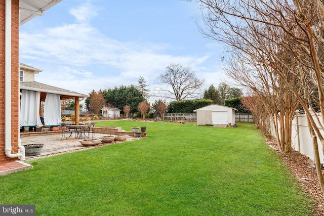 view of yard featuring a shed, an outdoor structure, a fenced backyard, and a patio