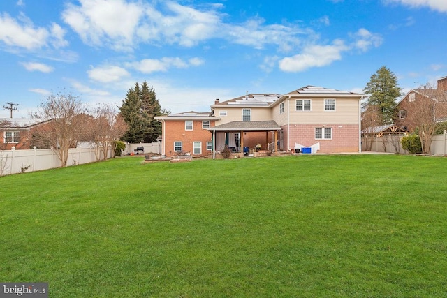 back of property with a patio area, a yard, a fenced backyard, and solar panels