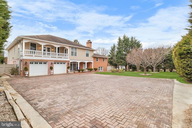 view of front of property featuring decorative driveway, brick siding, a chimney, a porch, and a front yard