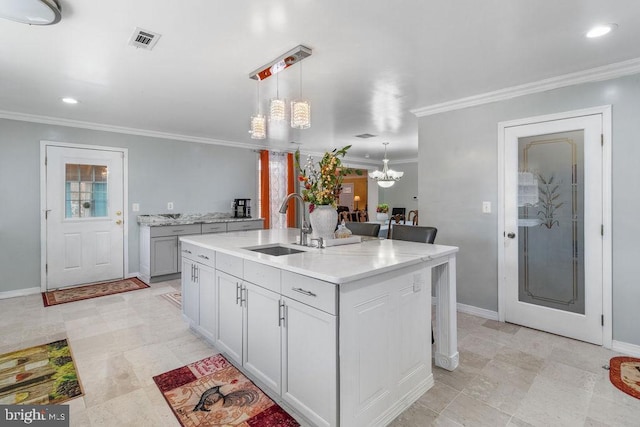 kitchen featuring visible vents, decorative light fixtures, an inviting chandelier, crown molding, and a sink