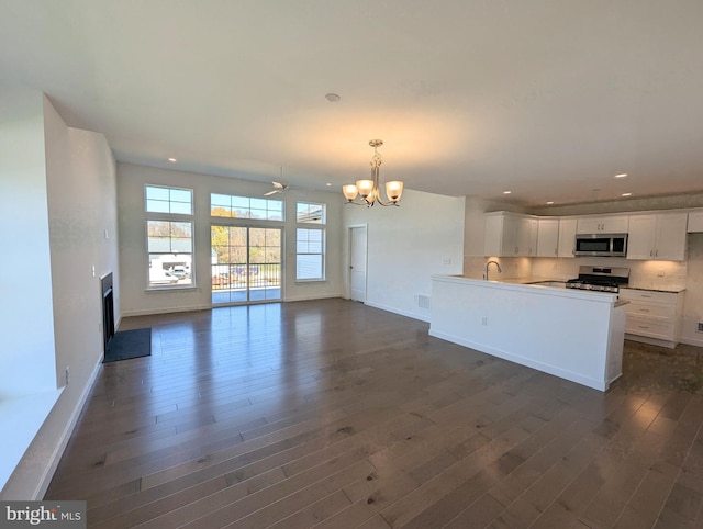 kitchen featuring white cabinets, appliances with stainless steel finishes, open floor plan, hanging light fixtures, and light countertops