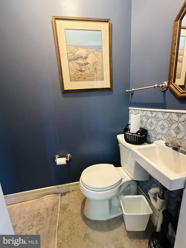 half bathroom with baseboards, a sink, and toilet