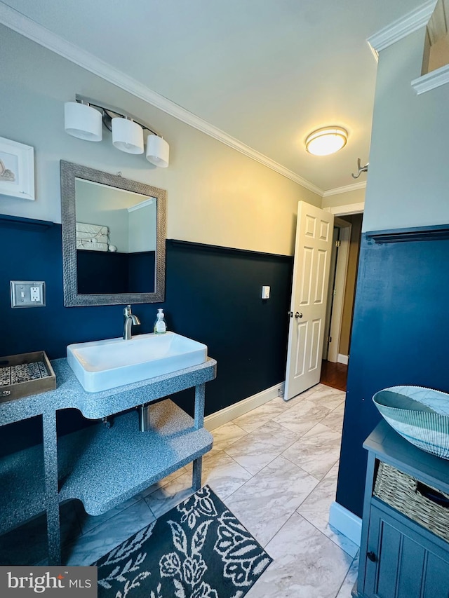 interior space with a sink, marble finish floor, baseboards, and crown molding