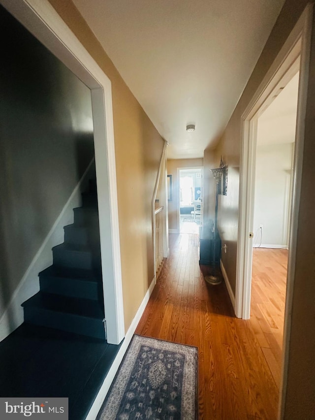 hallway with stairs, baseboards, and wood finished floors