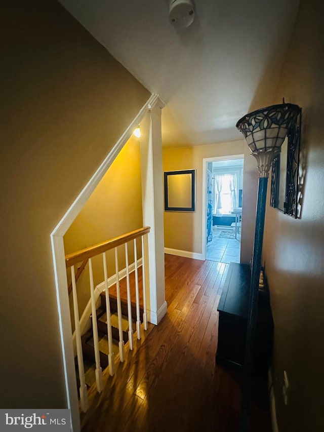 hall with baseboards, dark wood-type flooring, and an upstairs landing