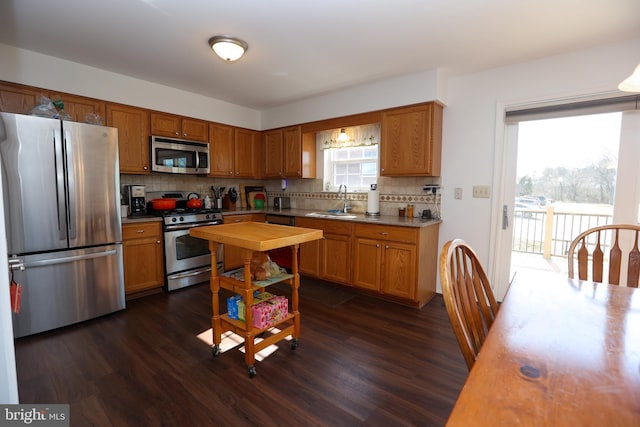 kitchen featuring decorative backsplash, appliances with stainless steel finishes, dark wood-type flooring, and a sink