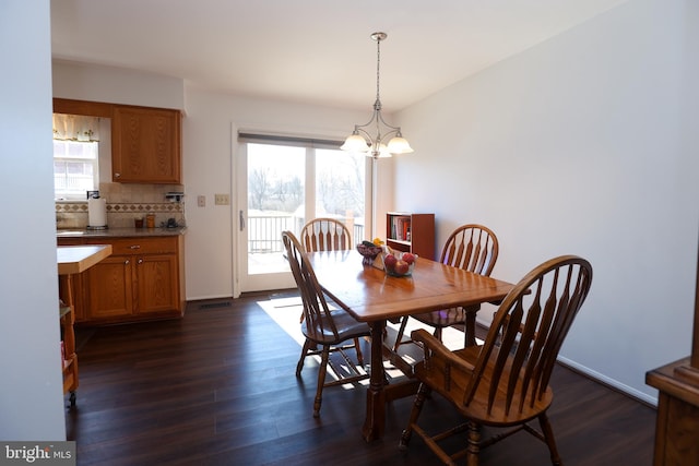 dining room with visible vents, dark wood finished floors, baseboards, and an inviting chandelier