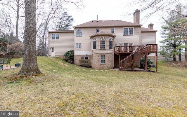 back of property featuring a lawn, stairs, a wooden deck, brick siding, and a chimney