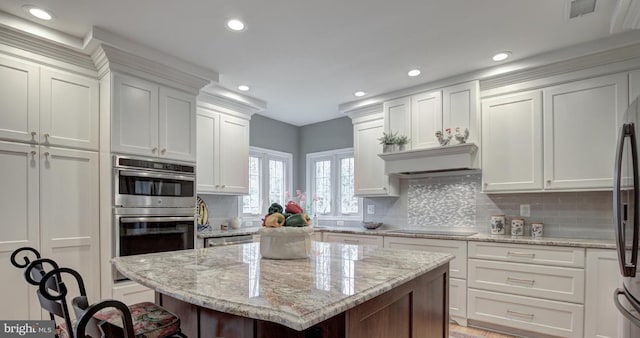 kitchen with visible vents, a kitchen bar, backsplash, white cabinetry, and stainless steel appliances