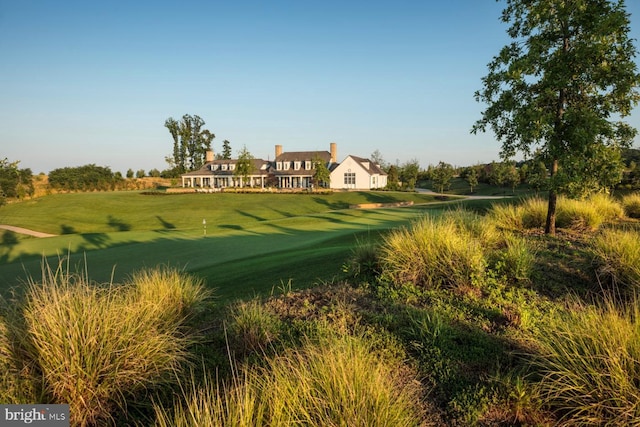 surrounding community with view of golf course and a lawn