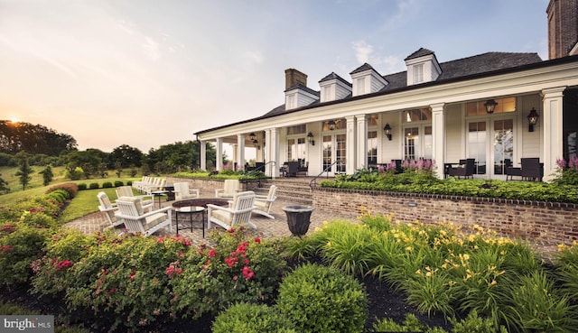 patio terrace at dusk featuring a porch and a fire pit