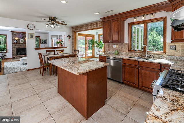 kitchen featuring stainless steel appliances, a sink, decorative backsplash, extractor fan, and a center island