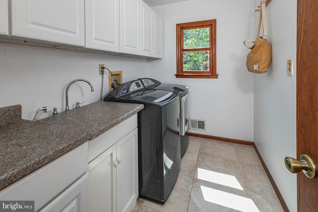 washroom featuring cabinet space, washer and dryer, baseboards, and light tile patterned floors