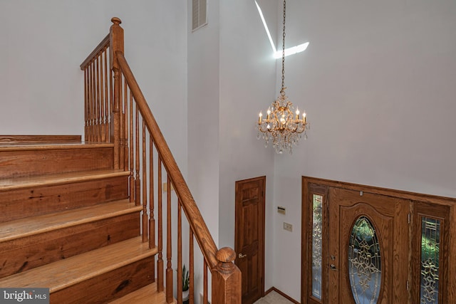entrance foyer with a towering ceiling, a chandelier, stairs, plenty of natural light, and baseboards