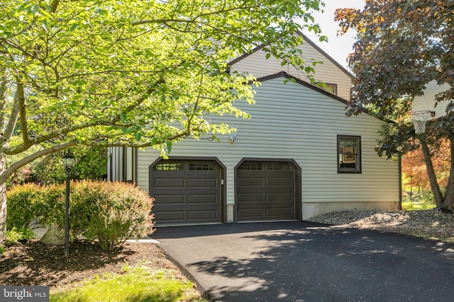 view of side of property featuring asphalt driveway and an attached garage