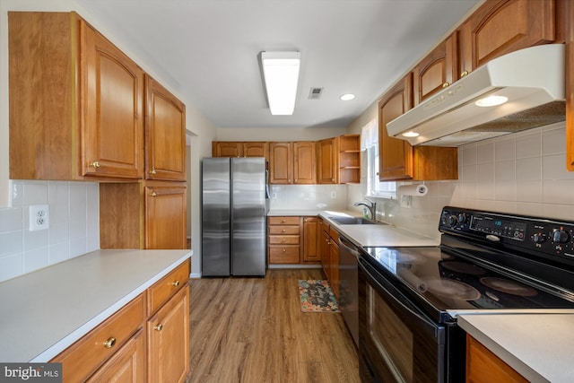 kitchen featuring under cabinet range hood, stainless steel appliances, a sink, light wood-style floors, and open shelves