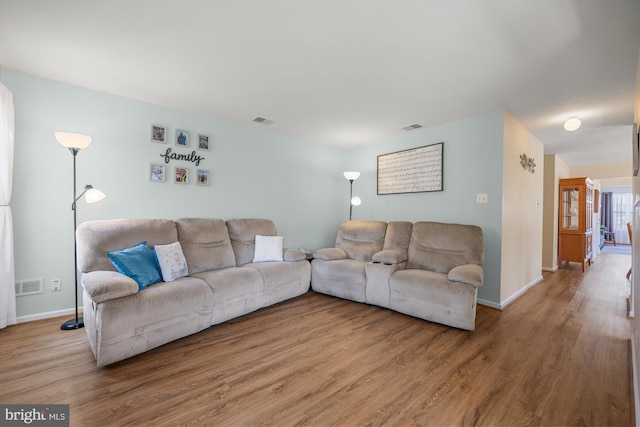 living area featuring wood finished floors, visible vents, and baseboards