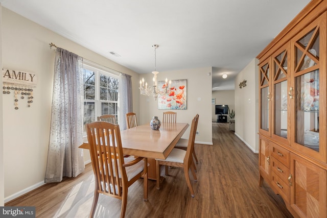 dining space featuring a chandelier, wood finished floors, visible vents, and baseboards