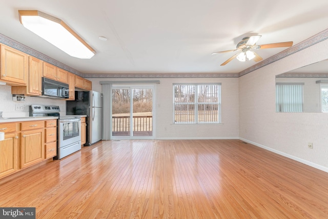 kitchen with light brown cabinets, stainless steel appliances, light wood-style floors, light countertops, and baseboards