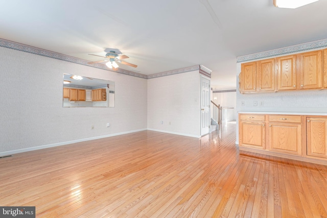 unfurnished living room featuring light wood-type flooring, baseboards, ceiling fan, and stairway