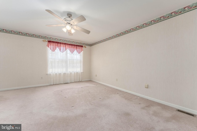 carpeted spare room featuring visible vents, ceiling fan, and baseboards