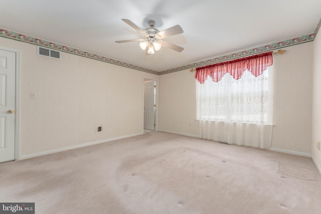 carpeted spare room featuring visible vents, ceiling fan, and baseboards