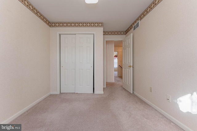 unfurnished bedroom with visible vents, carpet floors, baseboards, and a closet