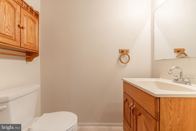 half bathroom featuring vanity, toilet, and baseboards