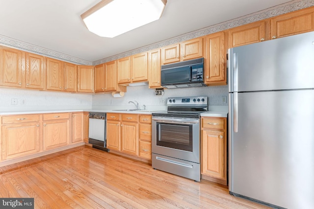 kitchen featuring light brown cabinetry, light wood-style flooring, stainless steel appliances, and light countertops