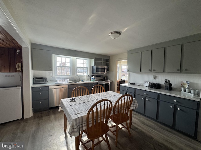 kitchen featuring light countertops, gray cabinetry, appliances with stainless steel finishes, dark wood-type flooring, and a sink