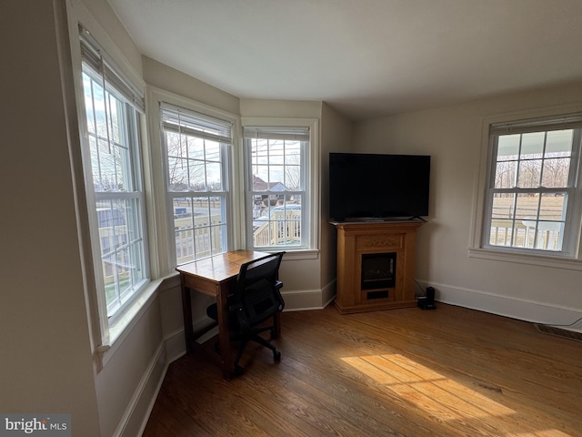 office space with a wealth of natural light, a fireplace, baseboards, and wood finished floors