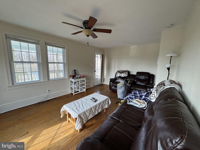 living room with ceiling fan, wood finished floors, visible vents, and baseboards