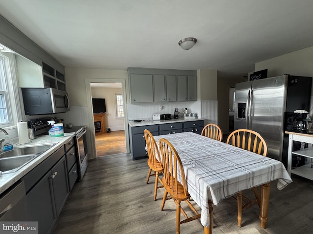 kitchen with dark wood-style floors, appliances with stainless steel finishes, light countertops, gray cabinetry, and a sink