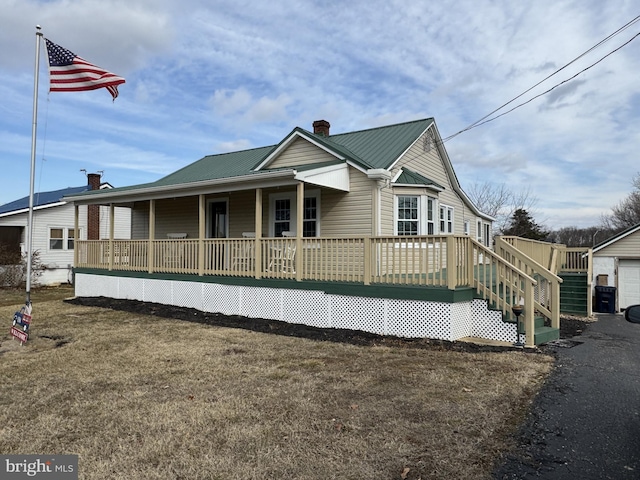 view of front of property featuring a chimney, metal roof, and a front yard