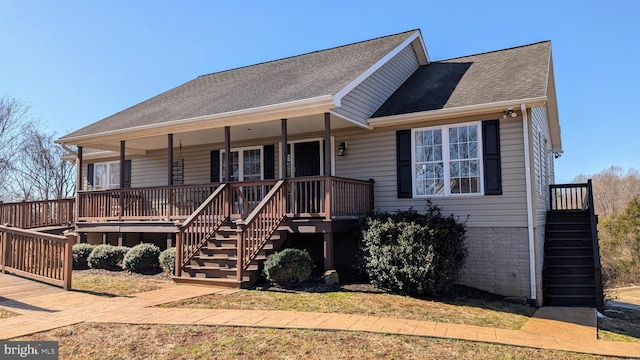 view of front of house featuring stairs, brick siding, roof with shingles, and a porch